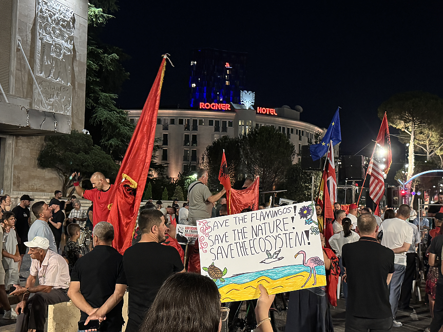 Протестиращ в Тирана държи ръчно нарисуван плакат с надпис
